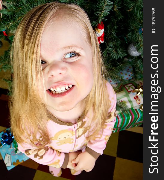 Funny picture of a child standing in front of a christmas tree with presents smiling. Funny picture of a child standing in front of a christmas tree with presents smiling.