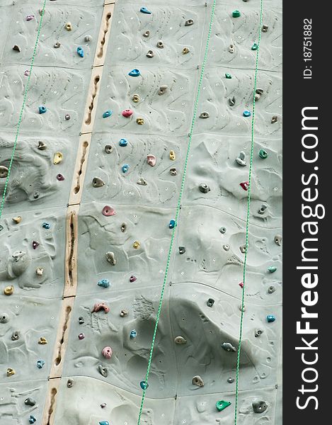 A portrait of climbing wall with hand grips and ropes