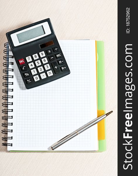 Notebook, silver ballpen and calculator on wooden desk. Notebook, silver ballpen and calculator on wooden desk