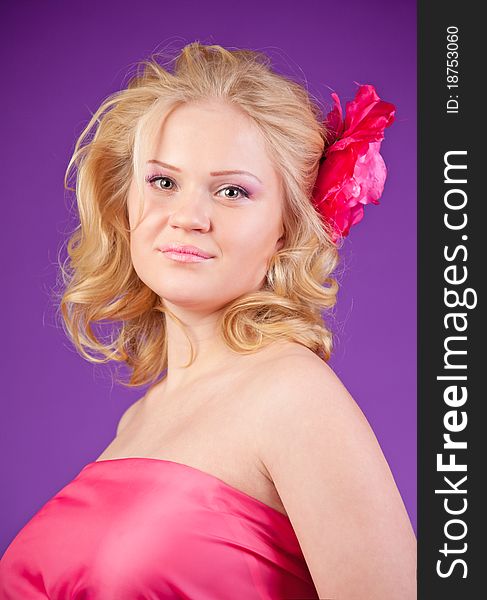 A young pregnant woman in a pink dress on the purple background. A young pregnant woman in a pink dress on the purple background