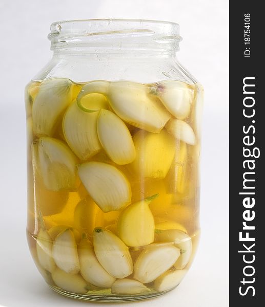 Cloves of garlic in the pot with sunflower oil isolated on white