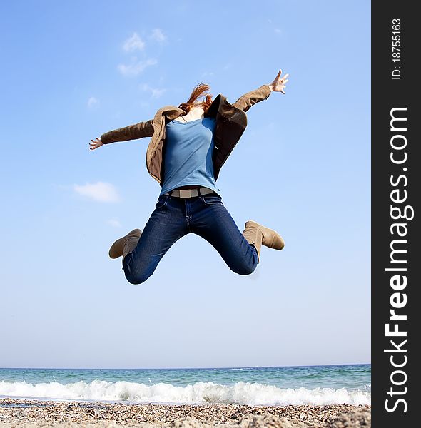 Young beautiful girl jumping at the beach.