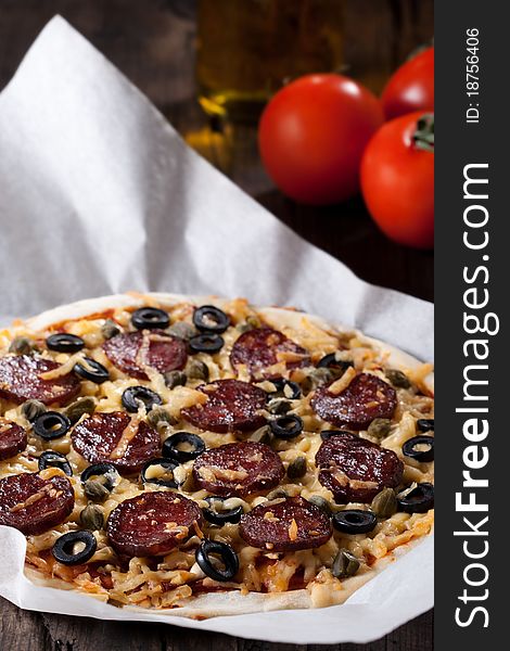 Homemade pizza with salami, cheese and black olives.
