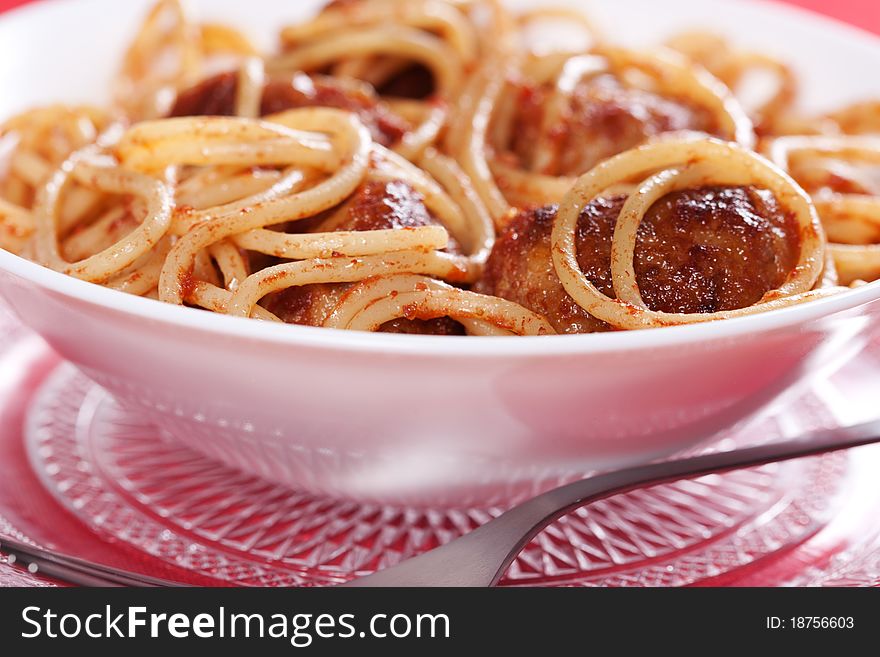 Pasta with meatballs and tomato sauce on red background