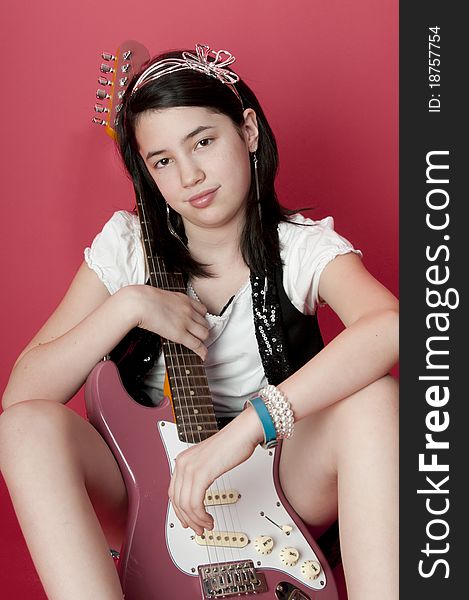 Preteen girl sitting on ground holding electric guitar. Preteen girl sitting on ground holding electric guitar