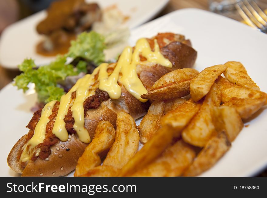 A plate of delicious sausage bread served with cheese and bolognese, accompanied by potato wedges and garnished, ready to be served!. A plate of delicious sausage bread served with cheese and bolognese, accompanied by potato wedges and garnished, ready to be served!