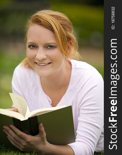 Young woman sitting outside reading. Young woman sitting outside reading