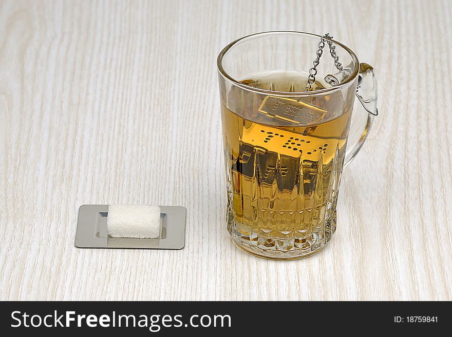 Glass of tea and sugar cube on textured background