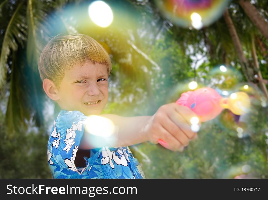 Boy playing with bubbles on natural background