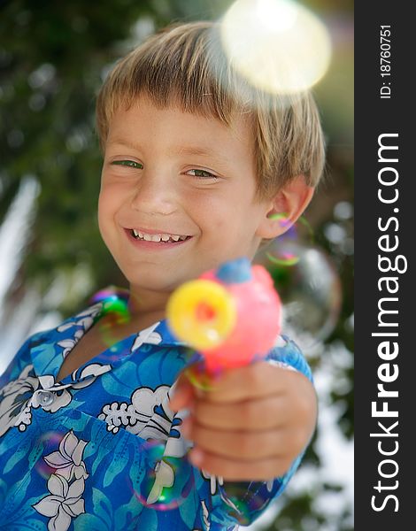 Boy playing with bubbles on natural background