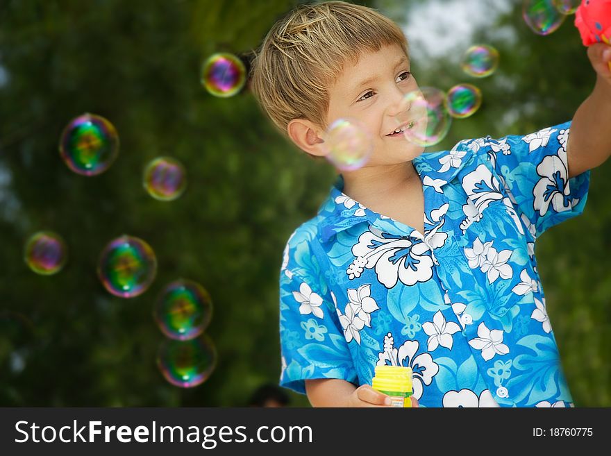 Boy playing with bubbles on natural background