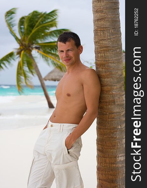 Young man on a tropical beach in the morning during a gale