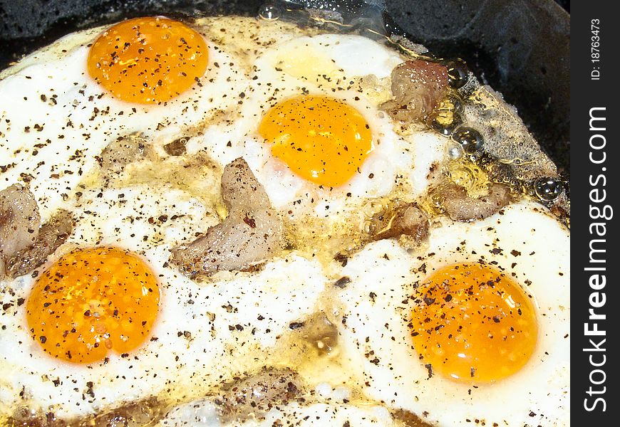 Scrambled eggs with bacon and spices in a pan