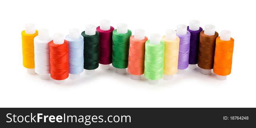 Spools multi-colored threads located a wave isolated on a white background