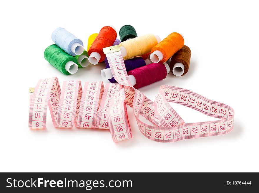 Spools Multi-colored threads randomly with a measuring tape of the tailor isolated on a white background. Spools Multi-colored threads randomly with a measuring tape of the tailor isolated on a white background