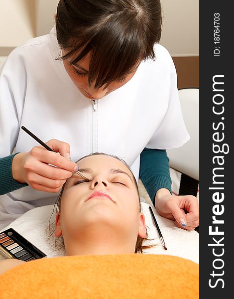 Cosmetician applying makeup for a client in the salon