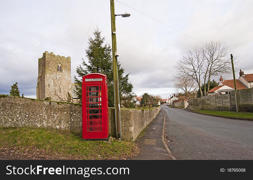 View through a traditional english countryside village with church and telephone box. View through a traditional english countryside village with church and telephone box