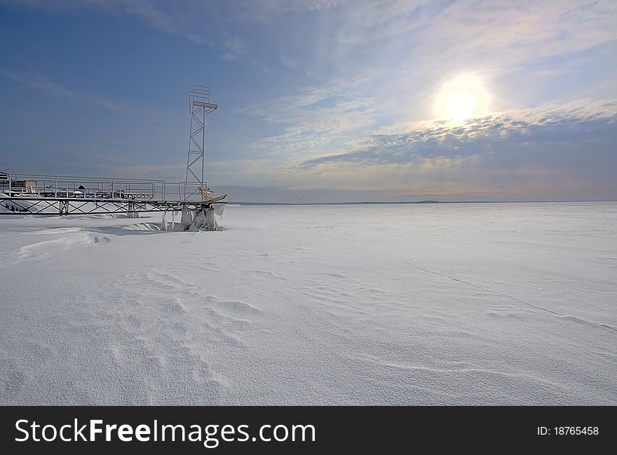 View of frozen sea, pier under snow and sunset, Russia. View of frozen sea, pier under snow and sunset, Russia.
