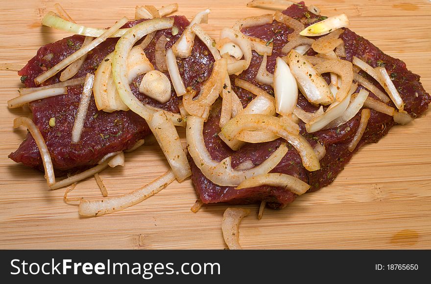 Marinated beef with onions on a cutting board. Marinated beef with onions on a cutting board.