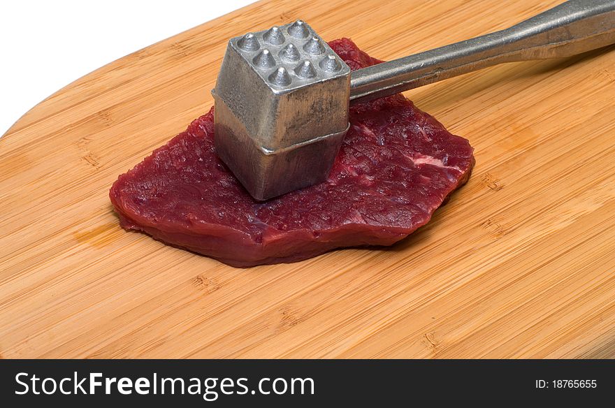 Piece of beef and a kitchen mallet on a wooden cutting board. Piece of beef and a kitchen mallet on a wooden cutting board.