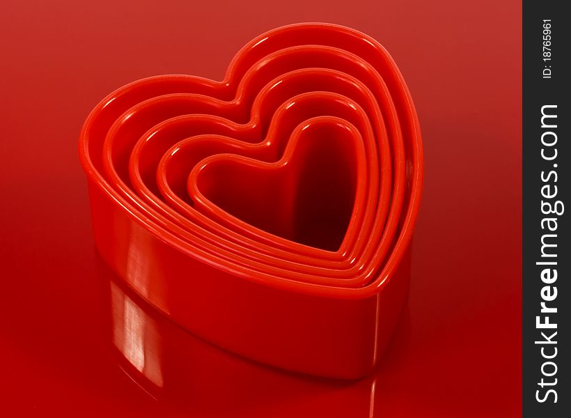 A closeup of red plastic cookie cutters on a red plastic surface