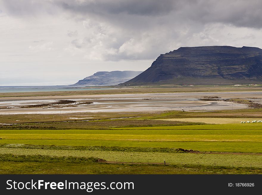Green farm, vestfjords in background big stony cliffs - Iceland. Green farm, vestfjords in background big stony cliffs - Iceland