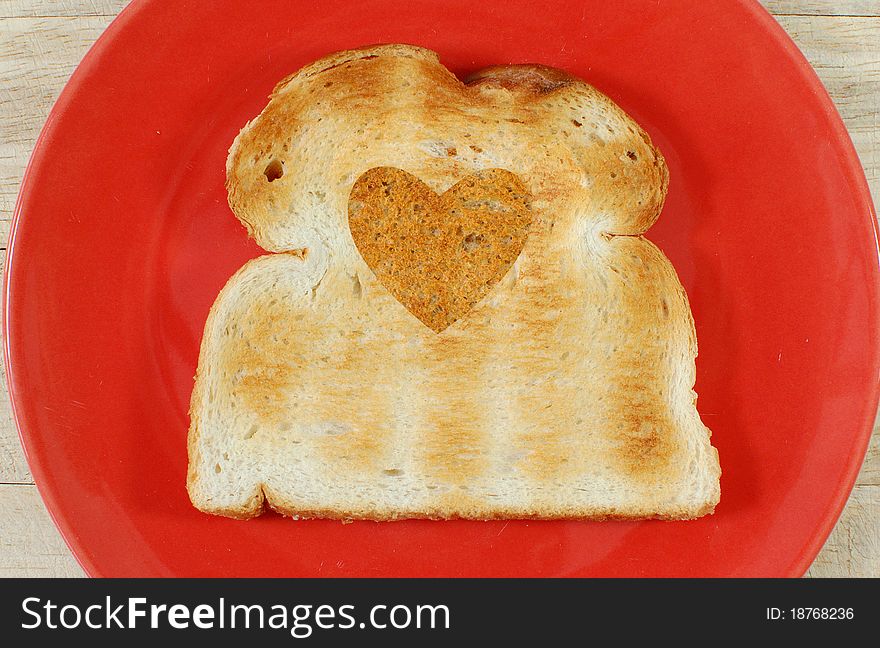 Heart made of wholegrain bread etched into a slice of white toast. Heart made of wholegrain bread etched into a slice of white toast
