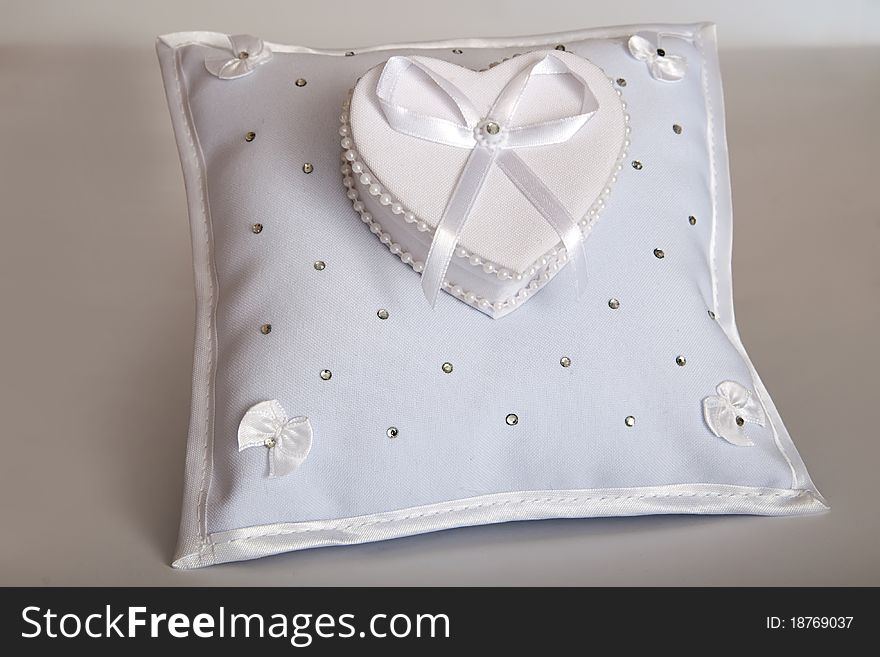 White pillow for wedding rings on the gray background