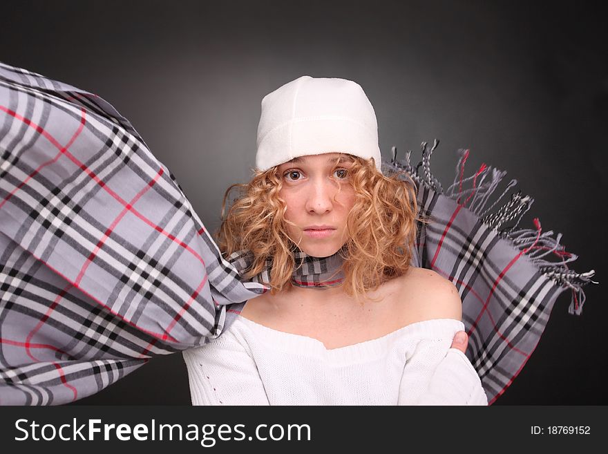 Upset curly blonde woman in hat with scarf flying round neck. Upset curly blonde woman in hat with scarf flying round neck