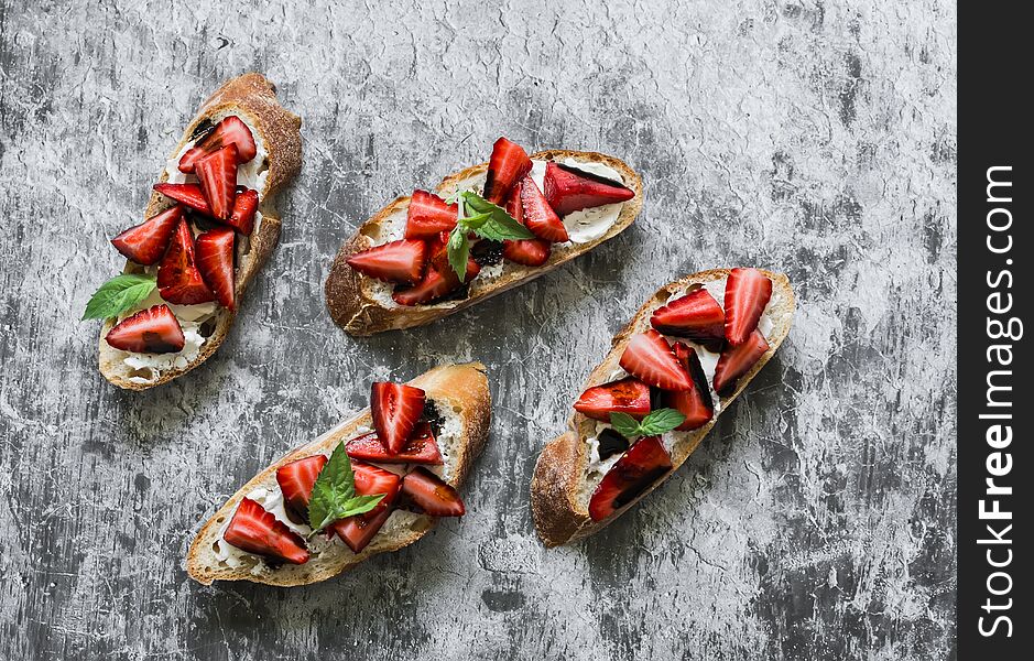 Bruschetta, Sandwiches With Strawberries, Cream Cheese And Balsamic Sauce On A Grey Background, Top View. Delicious Appetizer,