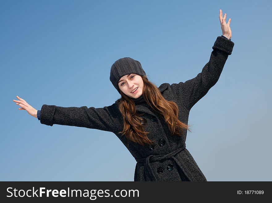 Pretty young woman with arms raised against blue sky