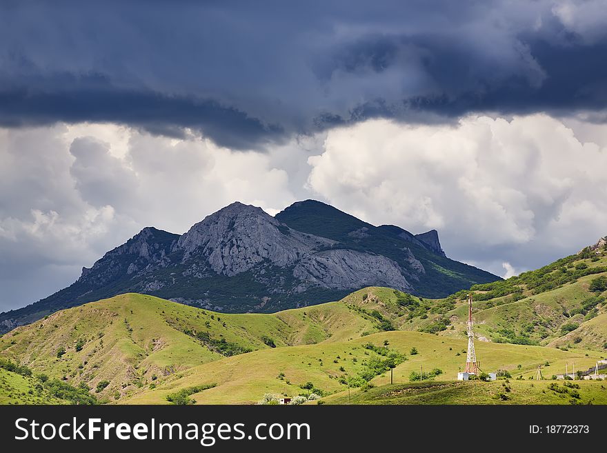 Drama clouds above mountains and a valley with telecommunication tower