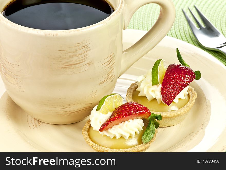 Key lime tarts with strawberries and a cup of coffee. Key lime tarts with strawberries and a cup of coffee