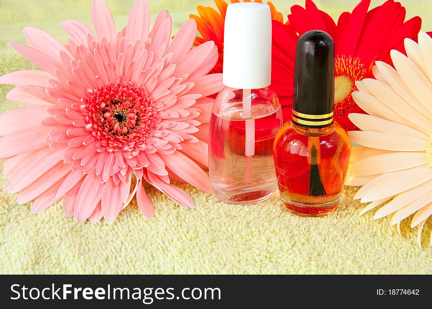 Nailcare product bottles with gerbera daisy flowers on light green towel. Nailcare product bottles with gerbera daisy flowers on light green towel