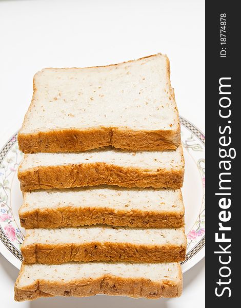 Sliced of whole wheat bread in a plate on white background