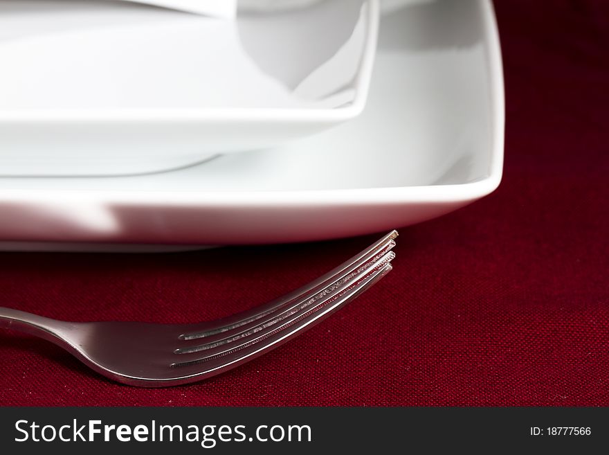 Fork on red tablecloth with white plates