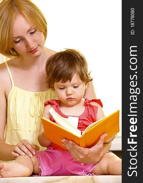 Young mother with her daughter reading book at home