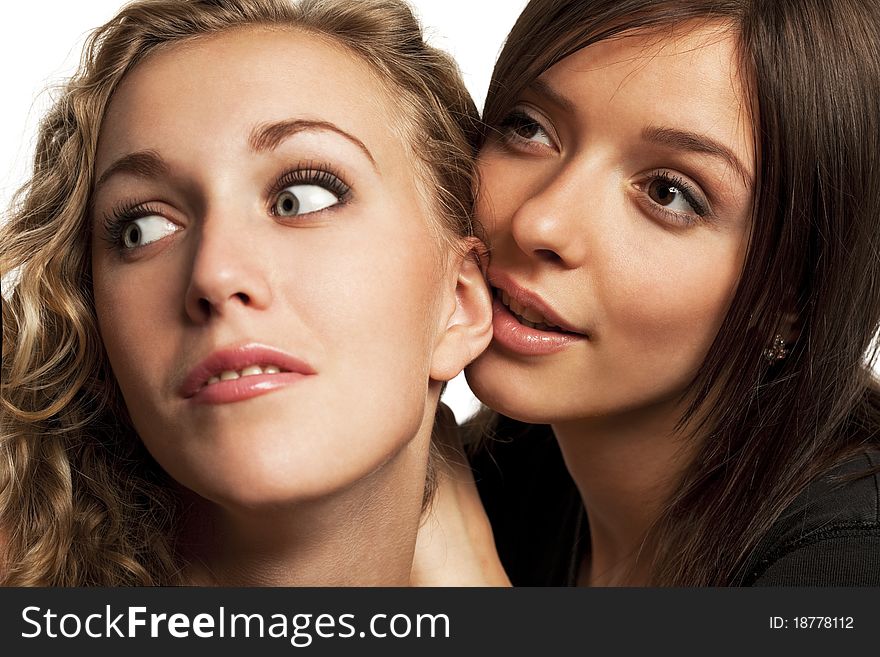 Two young girlfriends sharing their secrets, studio shot