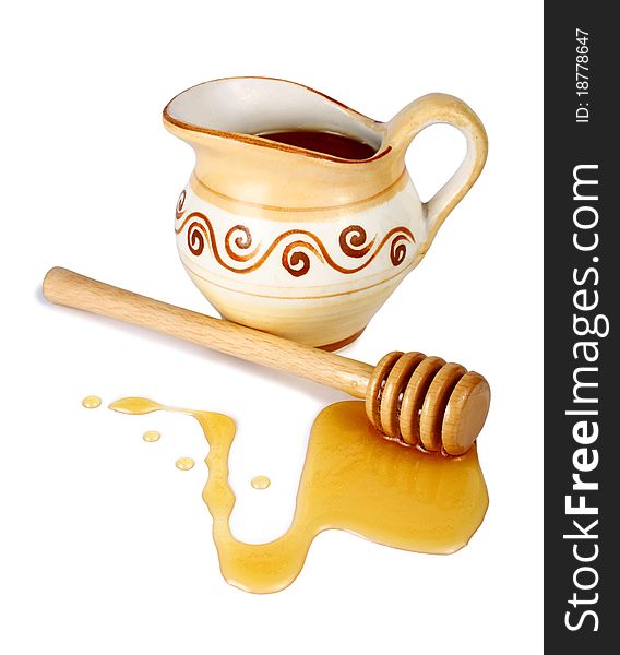 Honey in a jug and wooden stick isolated on white background
