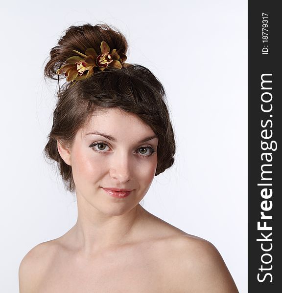 Portrait of the beauty young brunette girl with orchid in her hair