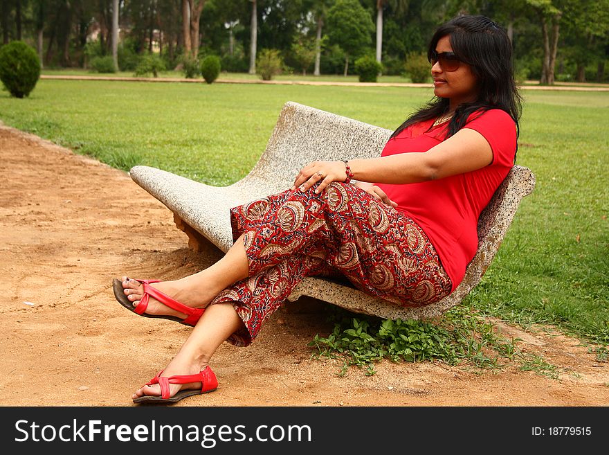 Woman Sitting On Stone Bench In A Park