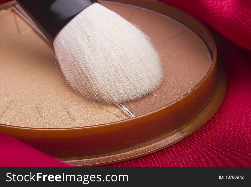 Powder brush and brown powder on a red background. Powder brush and brown powder on a red background.