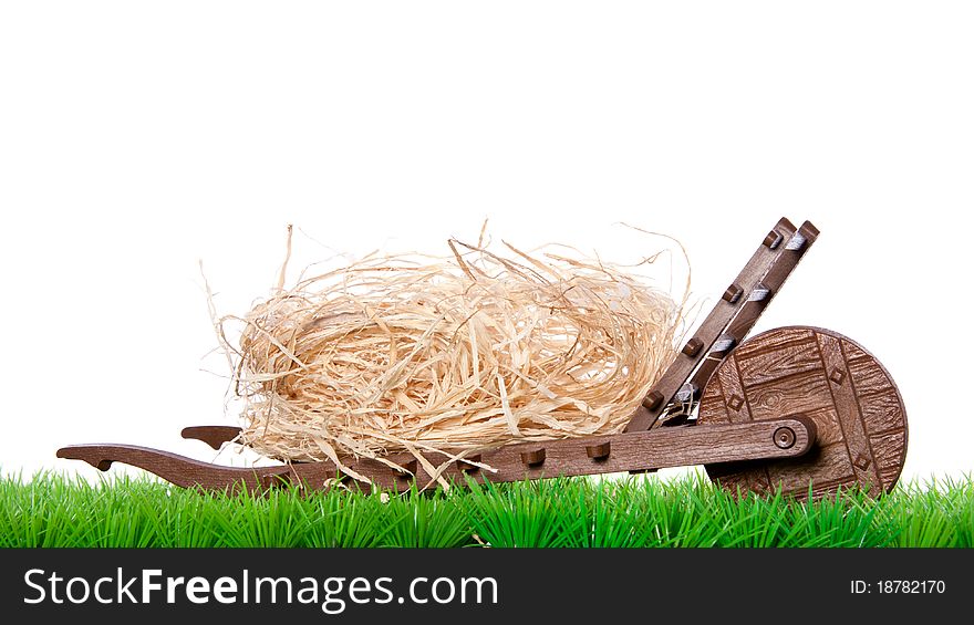 A transport wagon with dried straw on a green lawn isolated over white