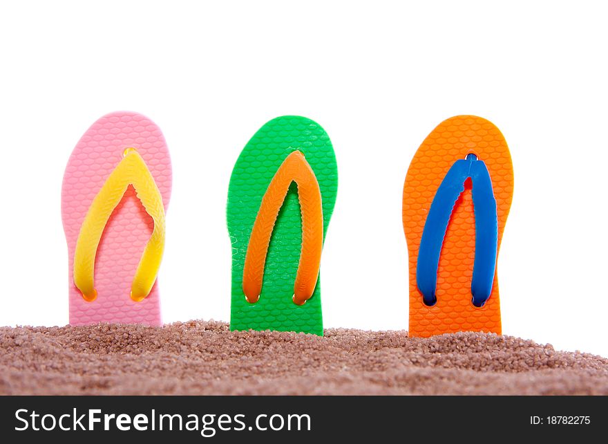Modern colorful summer thongs in beach sand against a white isolated backgroiund. Modern colorful summer thongs in beach sand against a white isolated backgroiund
