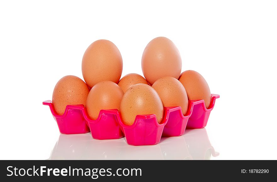 Many brown eggs in a pink plastic tray isolated over white