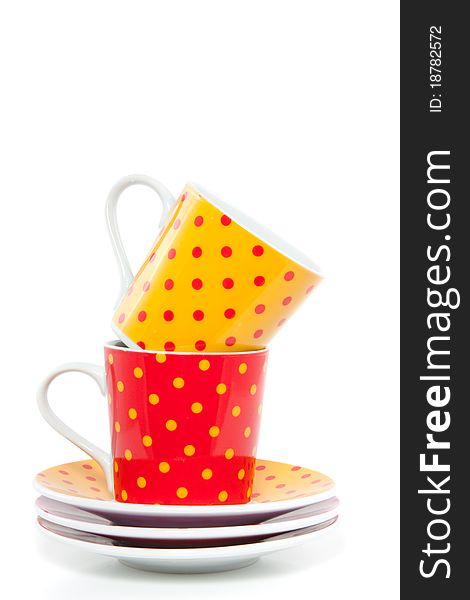 Colorful red and orange dotted cups and saucers isolated over white