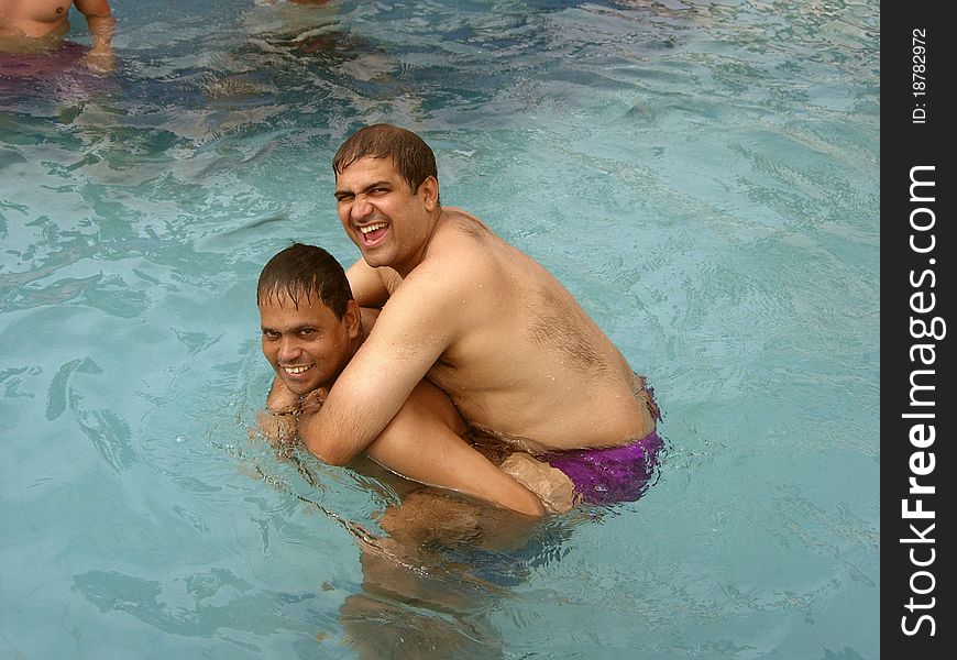 A dark Indian man lifting another in the swimming pool. A dark Indian man lifting another in the swimming pool.