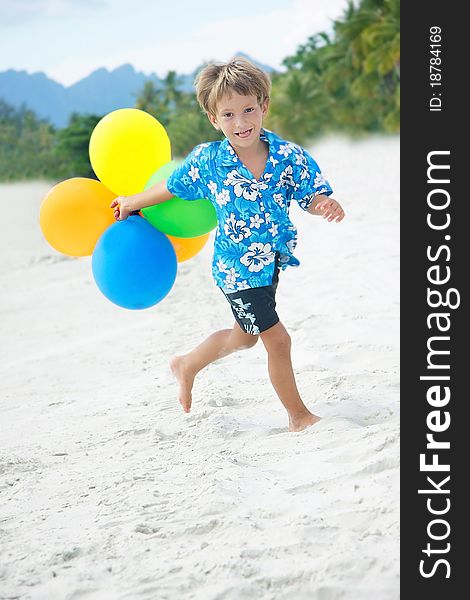 Young happy boy running with balloons on beach