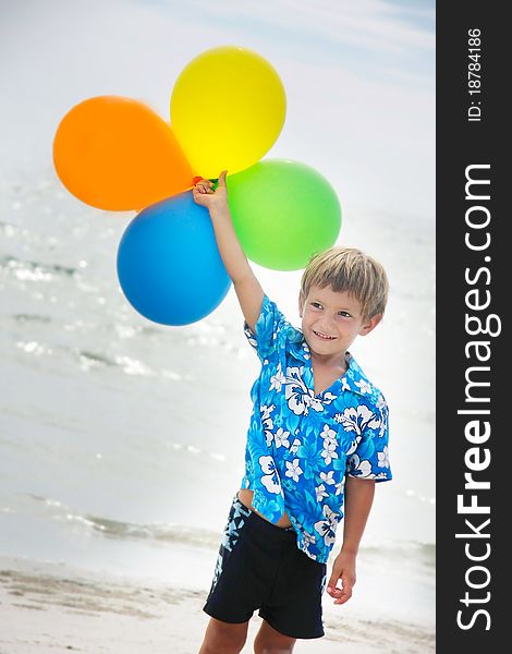 Young happy boy running with balloons on beach