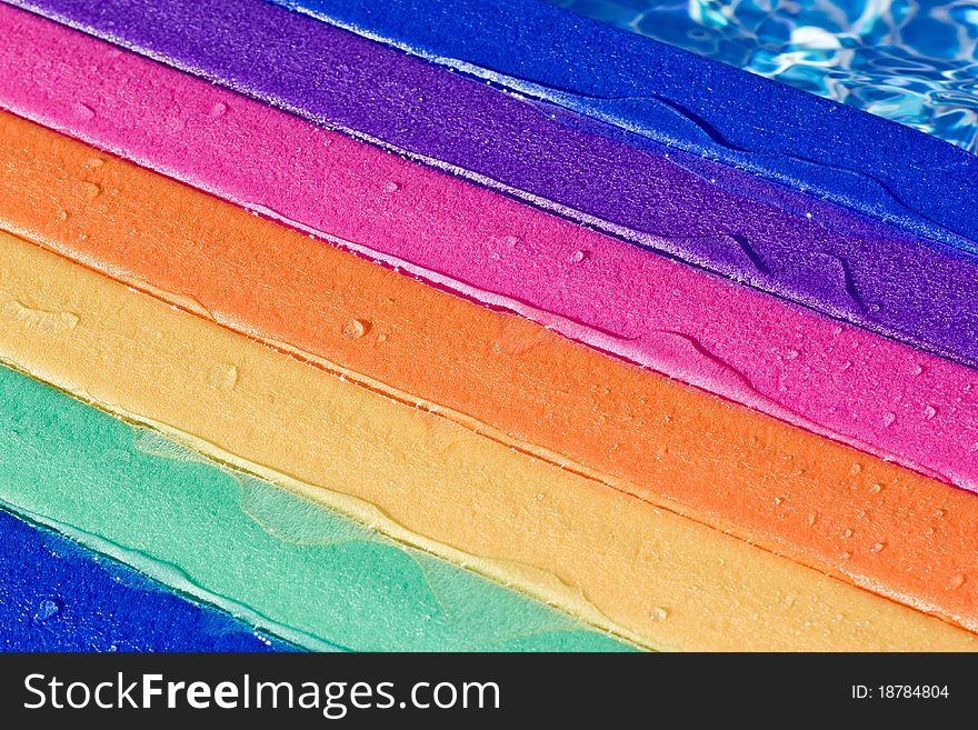 A rainbow colored water board in a pool with water on it. A rainbow colored water board in a pool with water on it